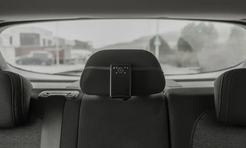 Cámara de vigilancia CarVig colocada en el reposacabezas del coche con batería externa